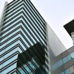 Low angle view of a modern skyscraper with glass facade reflecting the sky.