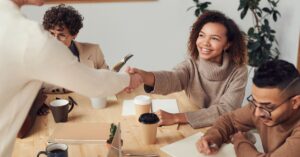 Colleagues in a positive meeting, exchanging a handshake while discussing projects.