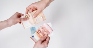 Close-up of hands exchanging euro bills, symbolizing finance and transaction.
