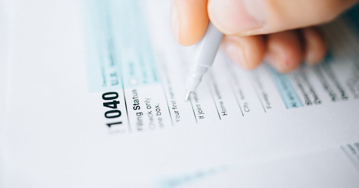 Close-up of a hand using a pen to fill out a tax form 1040, focusing on details.
