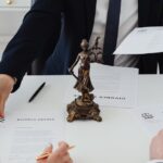 Three adults discussing divorce documents in a formal office setting with legal statue in view.