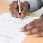 Close-up of a businessman signing a contract at an office desk.